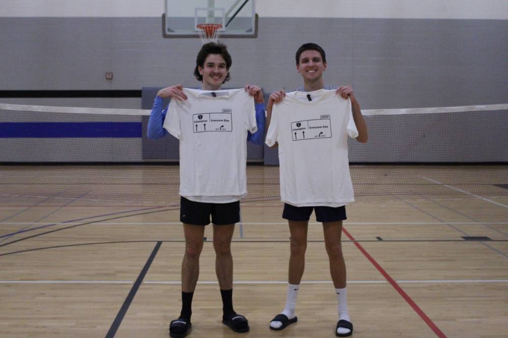 Students holding up championship shirts from a badminton tournament